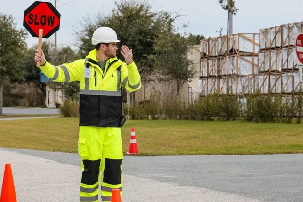 High visibility worker standing in busy urban traffic environment with reflective safety clothing
